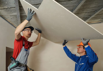 two men installing drywall on ceiling